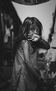 greyscale photo of girl covering her mouth holding broom stick