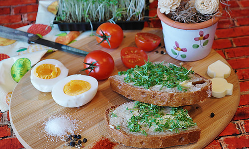 cooked eggs, tomatoes, and breads served on brown wooden tray