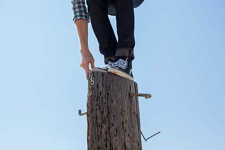 person on black pants standing in brown wooden log