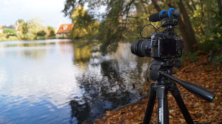 black DSLR camera with tripod stand near body of water