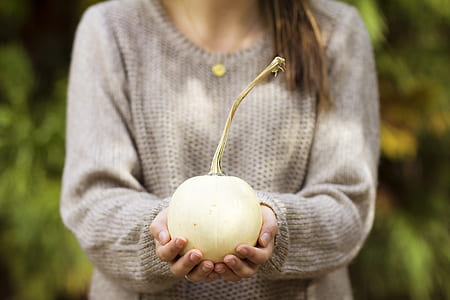 woman wearing gray knitted shirt holding white fruit