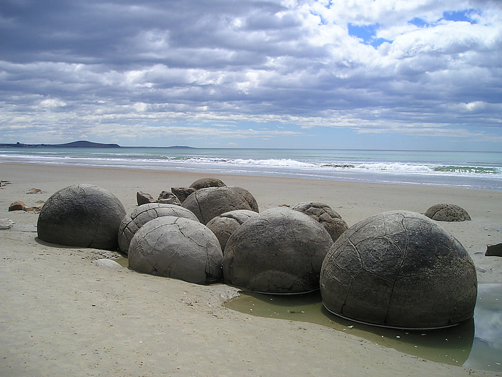 black rocks beside ocean during daytime