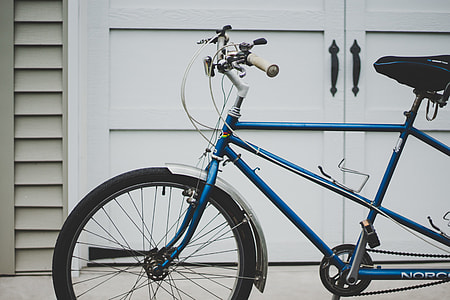 closeup photo of blue bike parked near white wooden door \