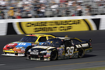 two black and yellow stock cars on gray road in full speed