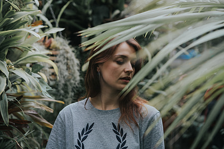 woman in gray and black floral crew-neck top surrounded by plants