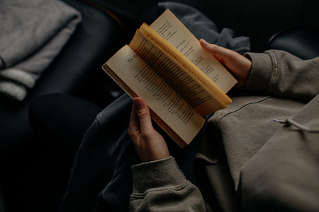 man wearing gray sweatshirt reading book