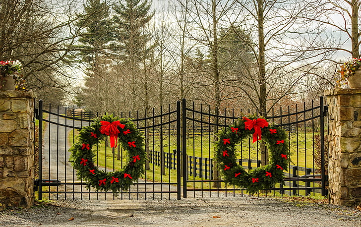 two large Christmas wreaths hanging on metal double gate
