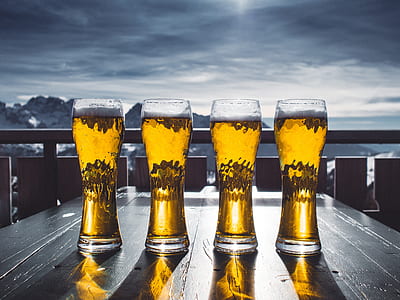 four beer mugs on table and mountain at distance