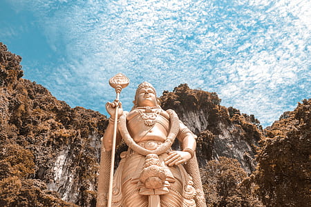 gold-colored Buddha statue with brown mountain in background under blue sky during daytime