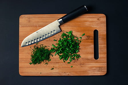 macro shot photography of chopped vegetables beside silver and black knife on brown wooden chopping board