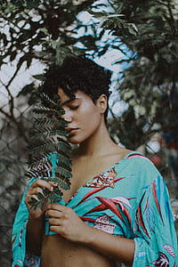 woman wearing blue and red crop shirt holding plant