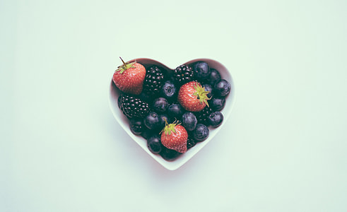 food photography of black berries and strawberries in heart shape bowl