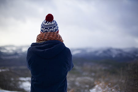 person in blue jacket, brown, scarf, and black and white bobble hat