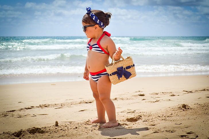 girl carrying beige wicker basket on beach shore during daytime