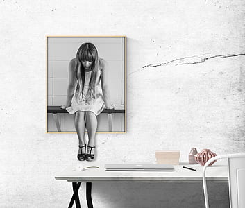 greyscale woman sittng on shelf painting