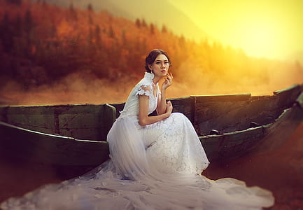 woman in white wedding dress beside canoe