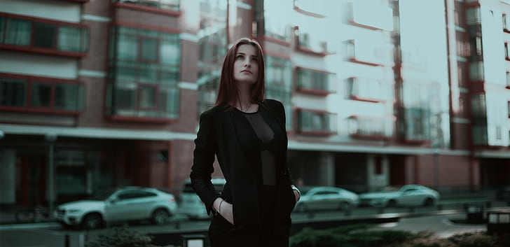 woman wearing black long-sleeved dress standing near building at daytime