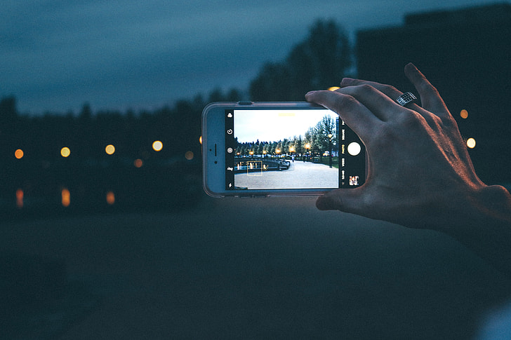Woman photographer taking a photo with her iPhone camera at night