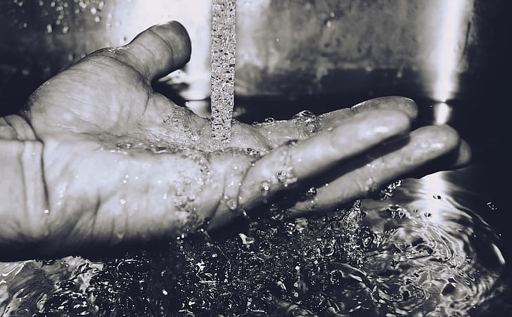 grayscale photography of pouring water on hand