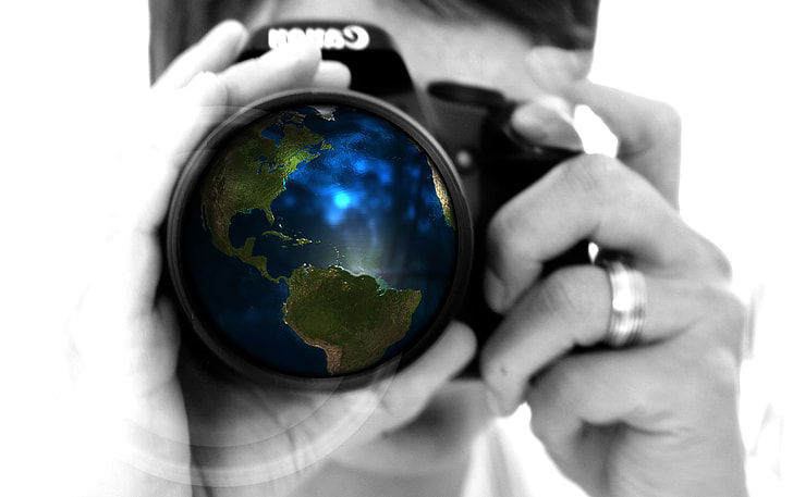 macro photography of man with DSLR camera with globe lens display