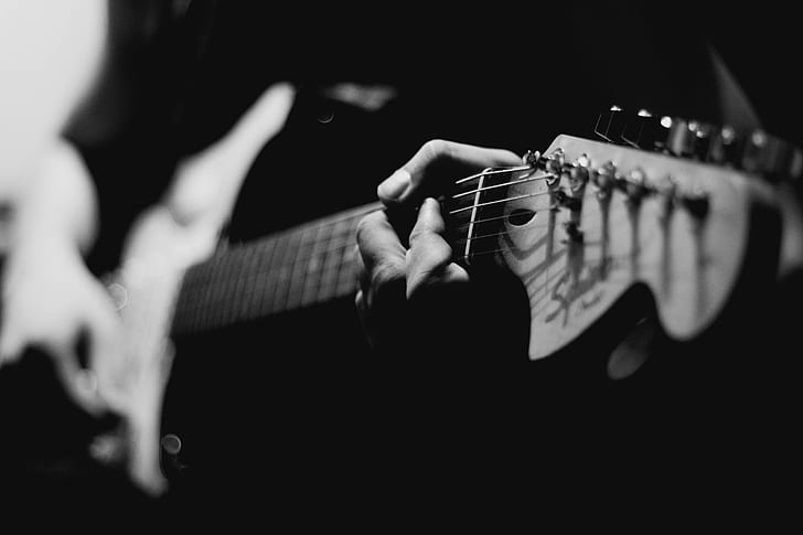 grayscale photo of man holding electric guitar