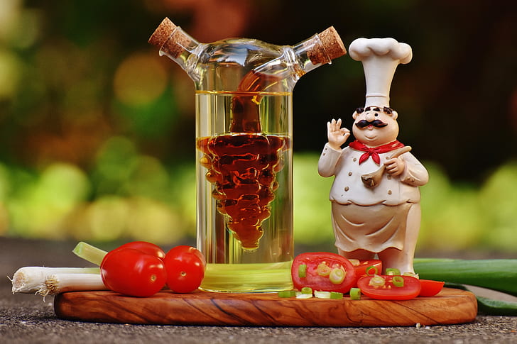 Chef Figurine Beside Clear Glass Bottle and Tomatoes