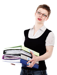 woman wearing black and gray polka-dotted collared shirt carrying four file binders
