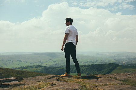 standing man in white T-shirt overlooking mountain