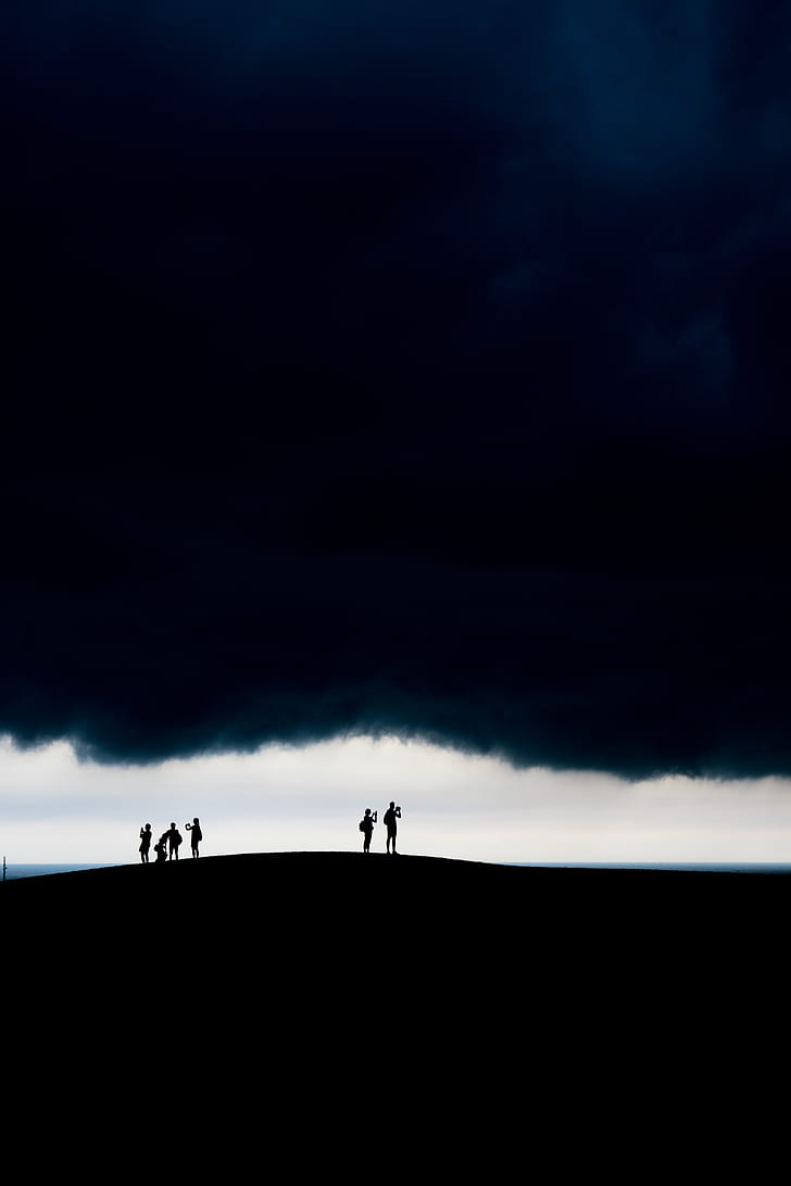 six people standing against white clouds