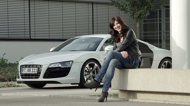 sitting woman in black leather jacket beside silver Audi sports coupe
