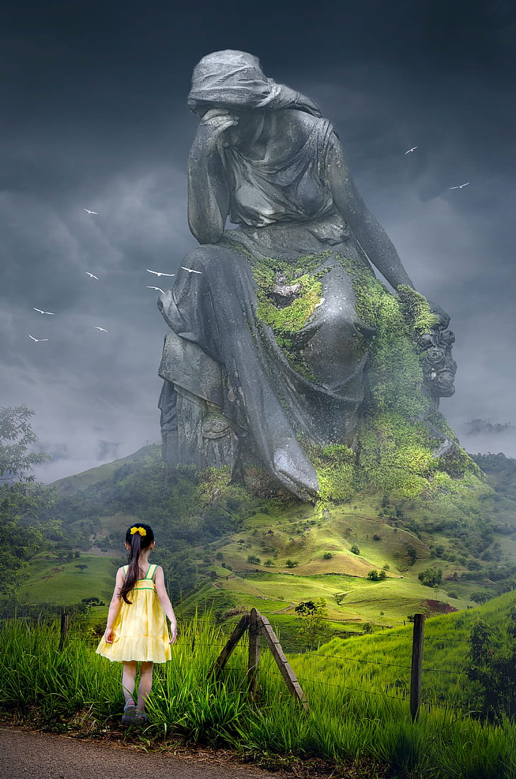 girl in yellow sundress in front of a giant woamn statue