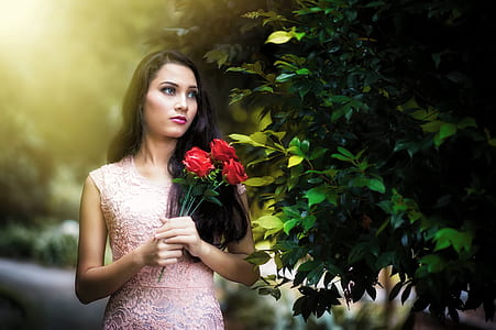 woman in pink dress holding red roses