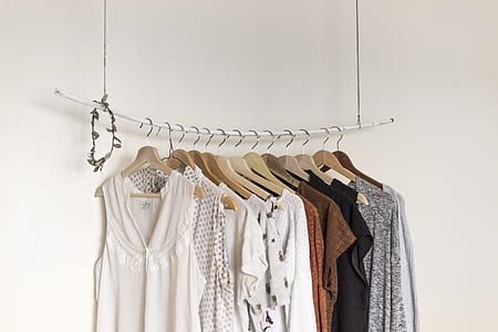 hanged assorted-color clothes beside white paint wall room