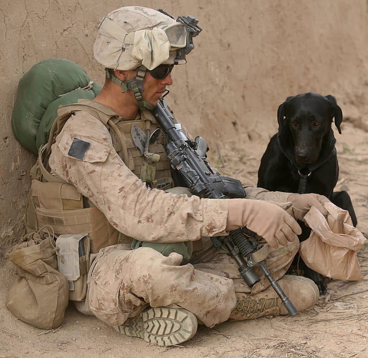 soldier sitting beside black dog
