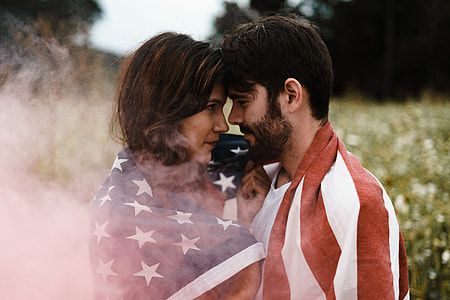 selective photography of man and woman face to face covered with U.S.A. flag