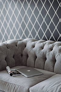 Elegant grey sofa with a laptop, an iPhone and a magazine