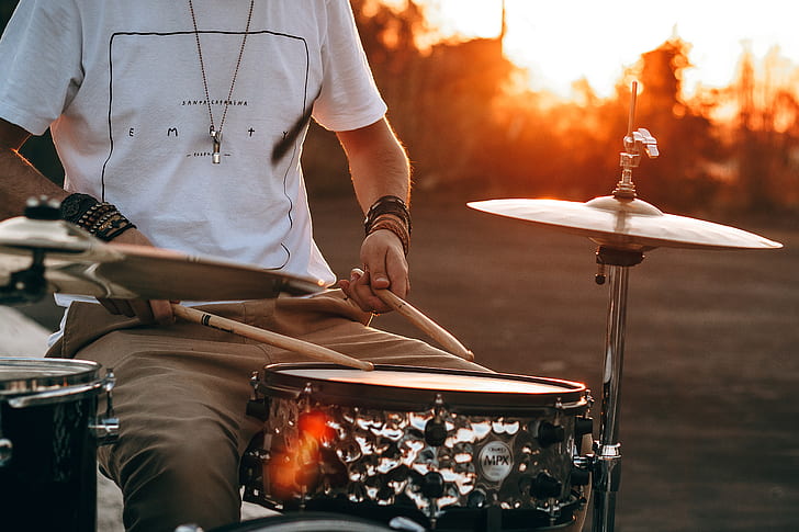 photography of man playing drum during golden hour