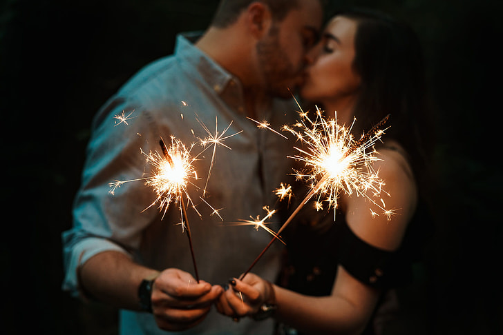 man and woman kissing while holding spark firecrakers