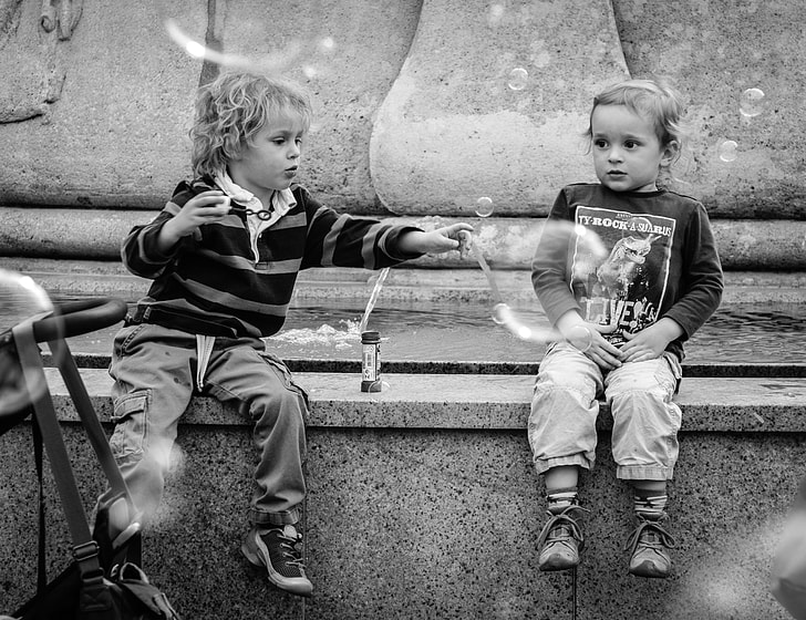 two boys near fountain grayscale photo