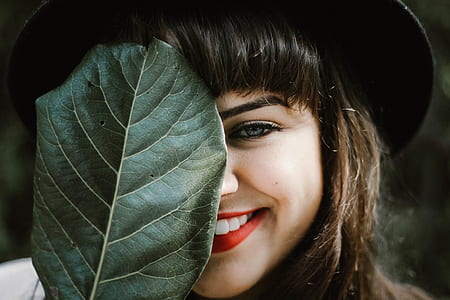 shallow photography of woman holding leaf