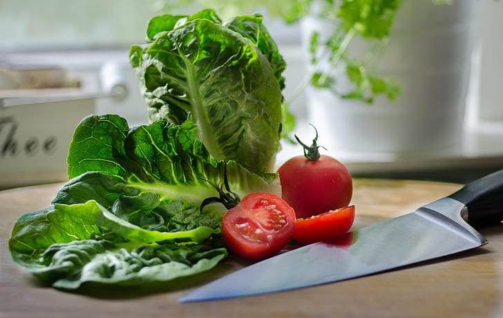 tomato and green leafy vegetable beside black handled knife