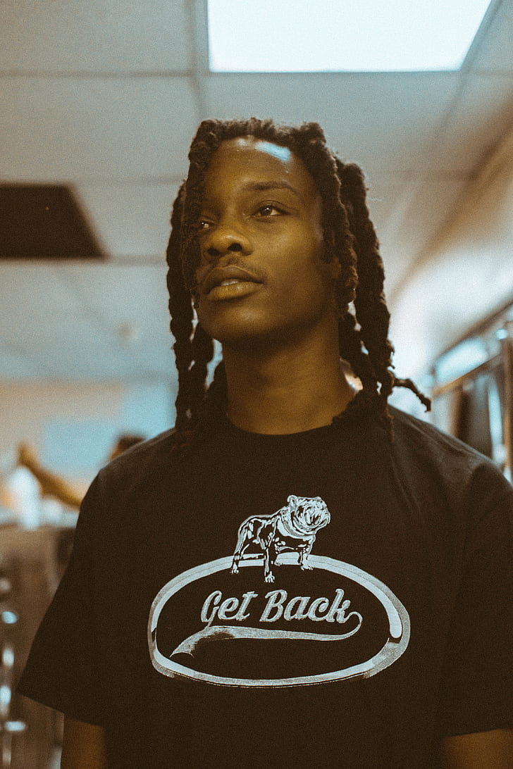 photograph of braid haired man in get back graphic shirt