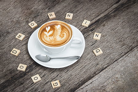 a cup of cappuccino with flower art and with scrabble letter words good morning greeting