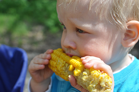 selective focus photography of boy eating corn