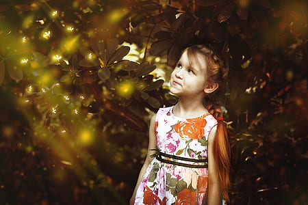 girl wearing white and orange sleeveless dress under green leaf tree