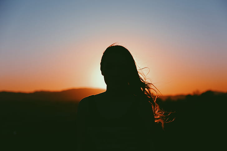 silhouette photo of woman staring at sun set