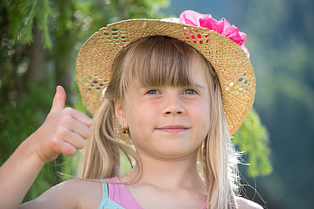 toddler's wearing brown and pink sunny hat and pink and teal top showing right thumb