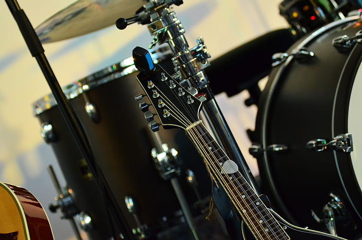 photo of black guitar beside drum set