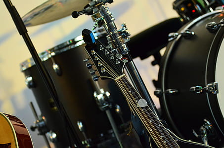 photo of black guitar beside drum set