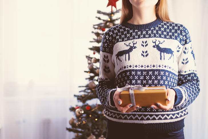 woman wearing blue and white sweater holding gift box
